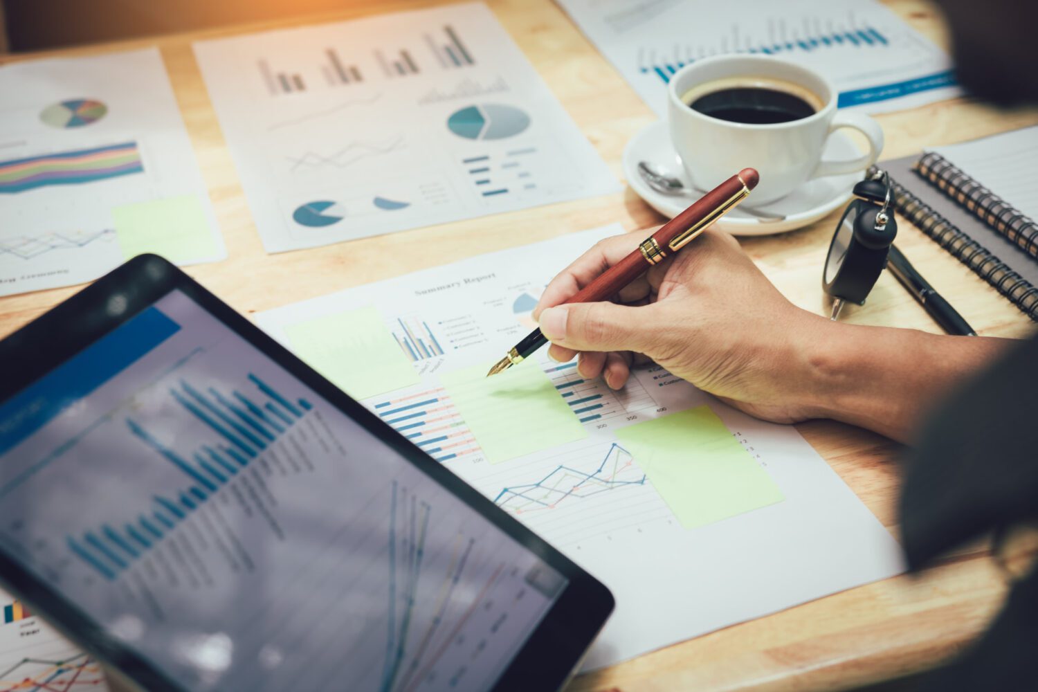 Businessman making note on sticky with looking graph in tablet.